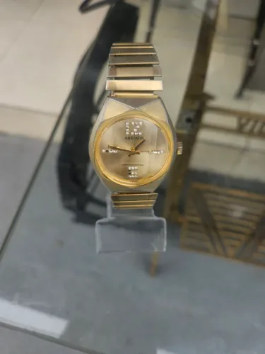 Relógio Aseikon em metal amarelo a corda
