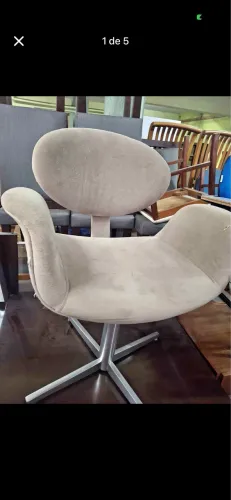 Cadeira giratória modelo Tulipa com estofamento em suede bege e base de alumínio.