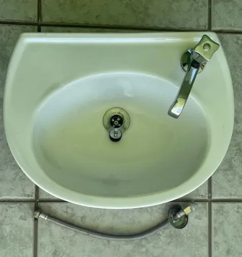 Lavatório oval branco Icasa, com válvula, torneira e chicote metálico 