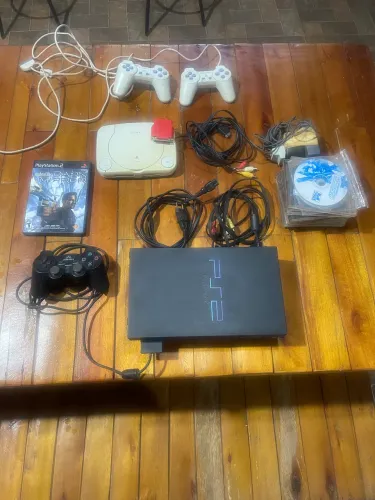 PlayStation 1 e 2 com controles e jogos