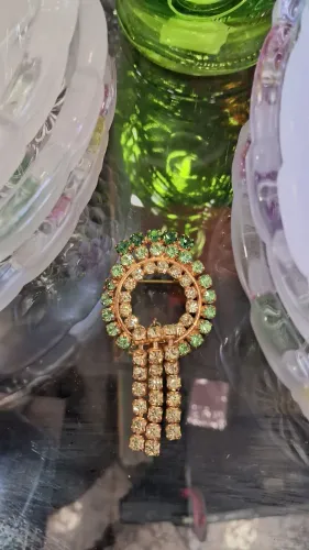 broche vintage em tom dourado, adornado com strass verdes e franjas pendentes