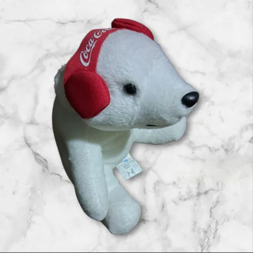 Ursinho de pelúcia branco com protetor de orelha Coca Cola
