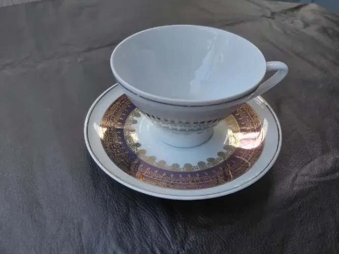 Xícara e pires de porcelana schmidt caracterizado por detalhes filetados a ouro e um padrã