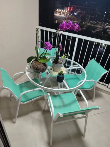 Mesa de vidro e quatro cadeiras de alumínio e tela sling verde, para varanda/área externa.