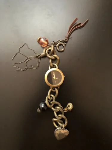 Relógio Stradivarius. Dourado envelhecido, mostrador preto e charms.