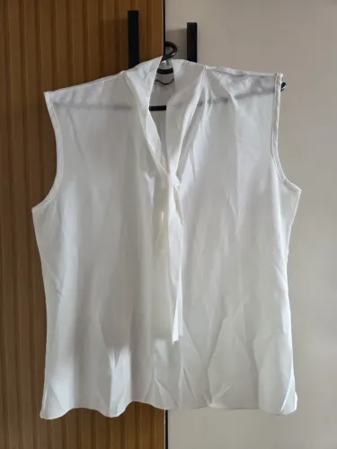 blusa regata branca sem mangas, feita de tecido leve com detalhe de gola alta, tamanho L/G