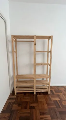 Guarda-roupa aberto de madeira com prateleiras e arara