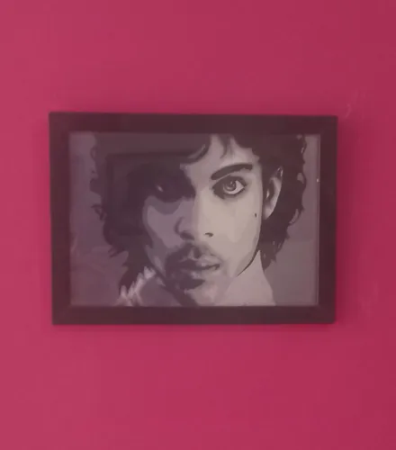 Quadro emoldurado em madeira e vidro com o rosto do cantor Prince em tom purple