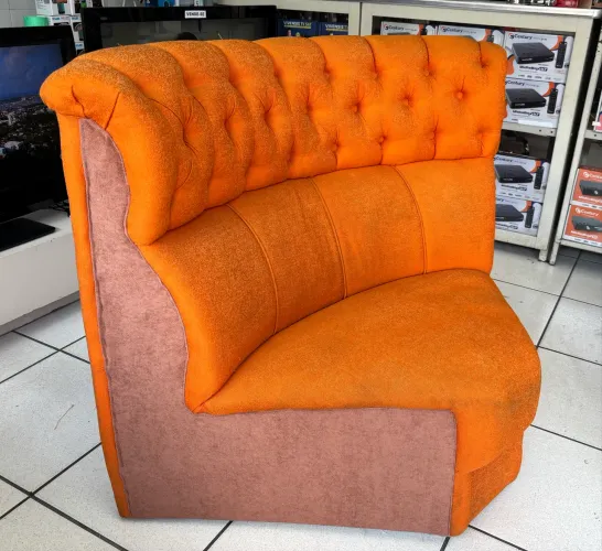 poltrona de canto estofada em laranja com encosto estilo capitonê.