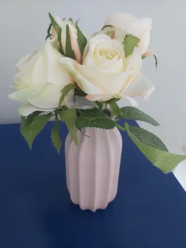 Vaso de cerâmica na cor rosa chá com flores off white e folhas verdes da Tok Stok.
