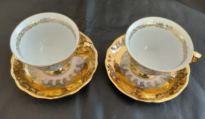 Par de xícaras antigas de porcelana dourada pintadas à mão com cena romântica