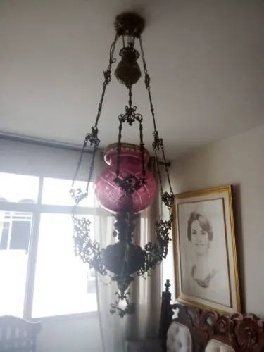 Lustre antigo em bronze possui uma cúpula de vidro rosa lapidado e estrutura trabalhada.