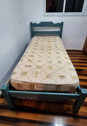 Cama de solteiro em madeira maciça com colchão.
