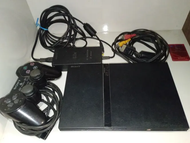 PS2 Super Slim com detalhe na carcaça e acessórios originais, lendo disco