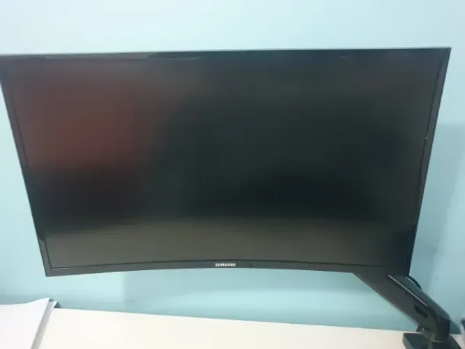 Monitor Curvo Samsung 27" com suporte de mesa articulado.