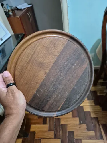 Bandeja redonda em madeira nobre com borda elevada medindo 26cm de diâmetro.