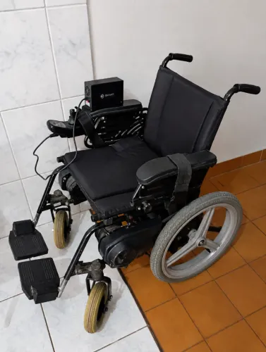 Vendo uma cadeira de rodas motorizada com um carregador.