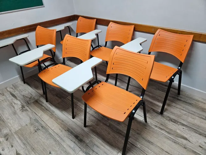 Lote com 6 carteiras escolares em aço com assento e encosto em plástico laranja.