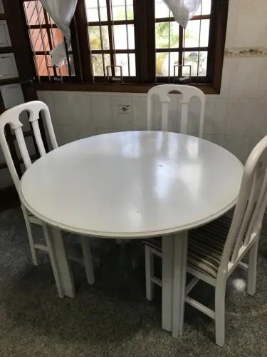 Mesa em madeira redonda com 4 cadeiras estofadas.