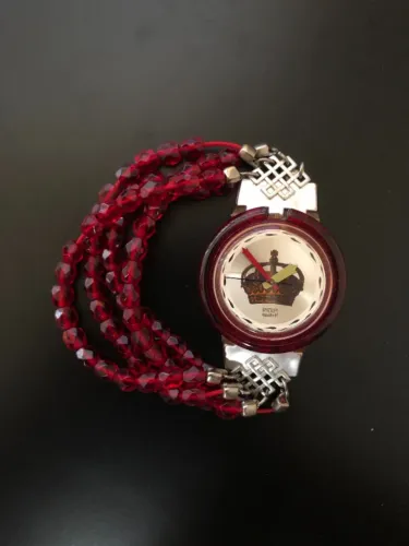 Pop Swatch vintage com coroa no mostrador e pulseira de contas vermelhas.