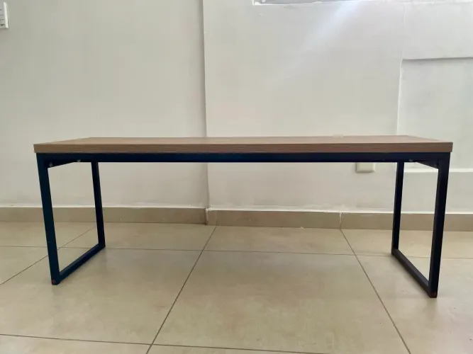 Mesa/banco estilo industrial, com tampo em madeira e pés de metal preto.