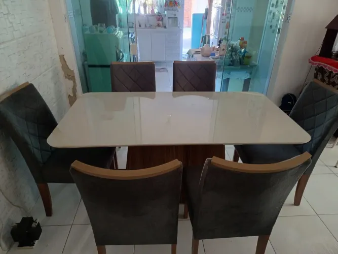 Mesa de jantar com seis cadeiras forradas e macias.