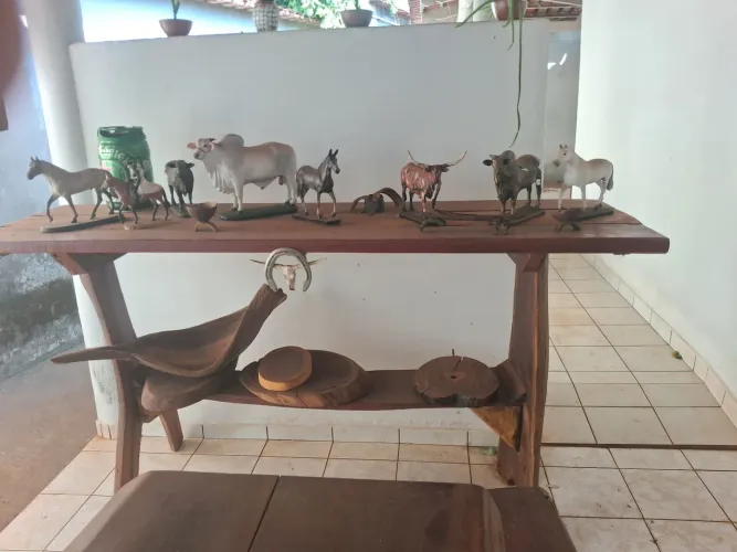 Aparador em madeira rústica com esculturas e tábuas de carne e fruteira.