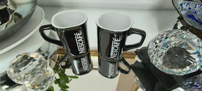 Duas canecas Nescafé Pretas.