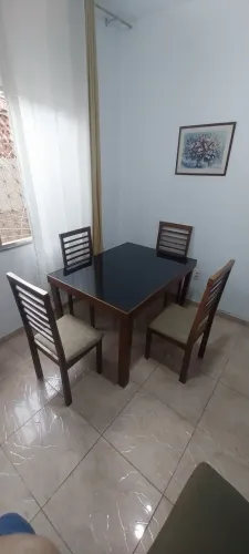 Mesa com quatro cadeiras em madeira com tampo de vidro.