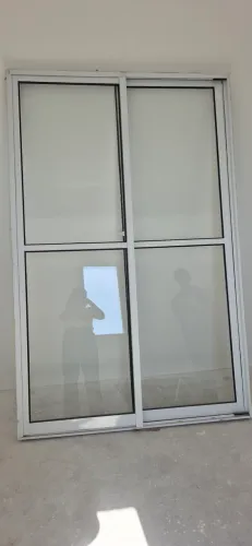 Porta balcão de correr em alumínio branco com vidros.