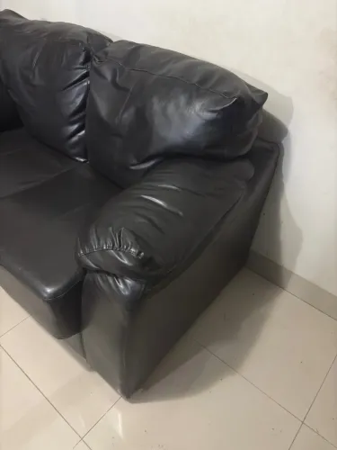 Sofá de Couro Preto e uma mesa para apoiar o pé ou decorar com algo