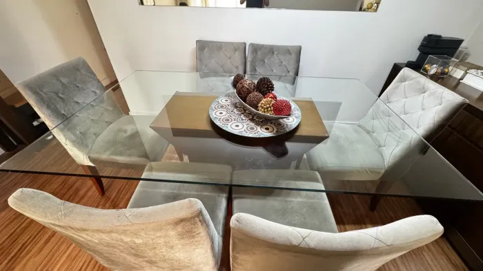 Mesa de vidro com 06 cadeiras estofadas na cor cinza.