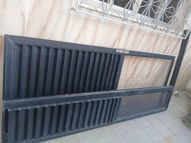 Porta de alumínio preta usada com detalhe veneziana e espaço para vidro basculante.