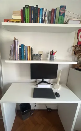 Escrivaninha branca de 110 x 45 cm com duas prateleiras suspensas.