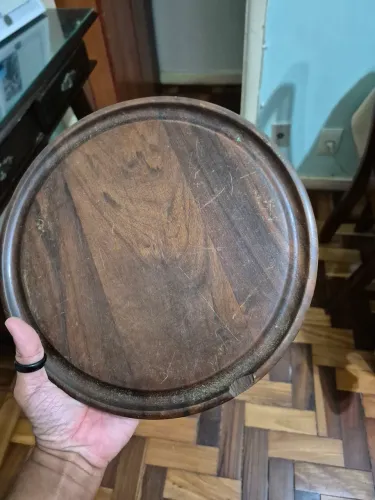 Bandeja redonda em madeira nobre com borda elevada medindo 26cm de diâmetro.