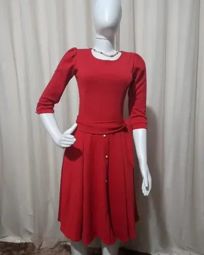 Vestido em malha abaixo do joelho, saia godê com botões, manga 3/4 e faixa.<br>
