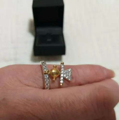 ANEL COM PINGENTE "MENINA", COM CRISTAIS E BANHADO A OURO, MARCA ATTRATTIVA.