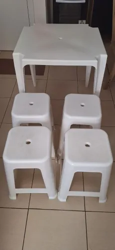Mesa de plástico com quatro banquetas.