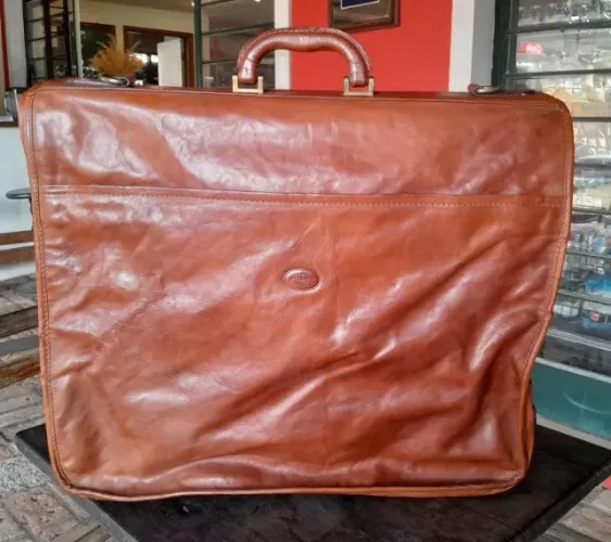 Porta terno, em couro natural, da marca The Bridge. 