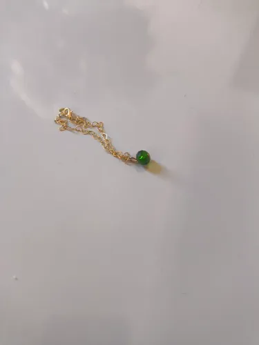Delicado colar de ouro com um pingente de pedra preciosa verde vibrante.