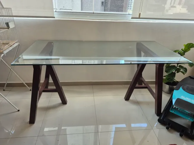 Mesa com tampo de vidro e cavaletes de madeira