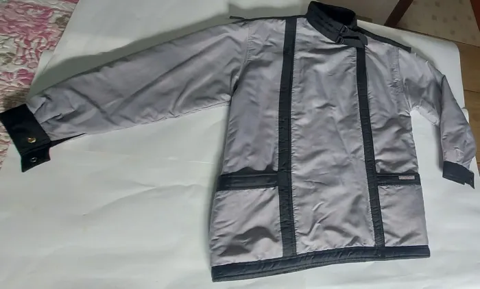 Casaco cinza com detalhes. Com 2 bolsos que vão até as costas, zíper e pescoço com garras