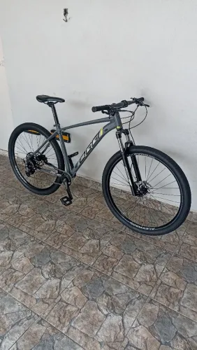 Bicicleta Oggi BW 7.0 cinza amarela e preta fechada de fábrica com grupo Shimano Cues