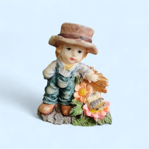 Bibelô vintage de resina italiana, representando garoto com martelo escorado na cerca.