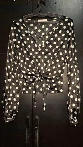 Blusa cropped preta com poá branca, decote em V cruzado e um charmoso nó para amarração.