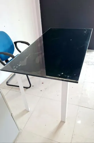 Mesa de escritório com tampa de vidro superior.