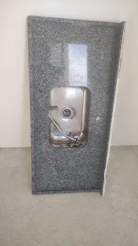 Bancada em granito cinza, pia em inox e torneira.