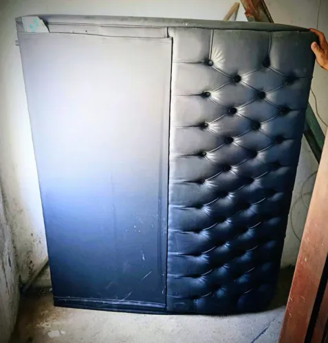 cabeceira de cama box estilo capitonê com revestimento em couro sintético preto.