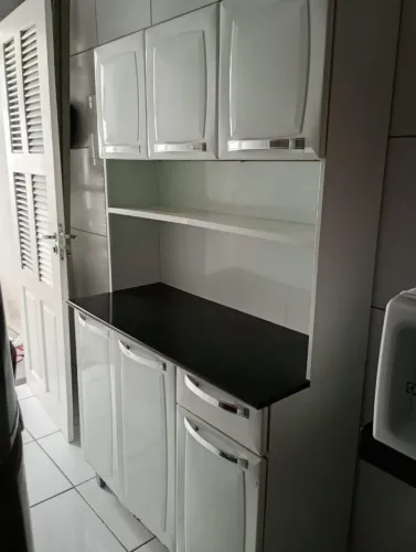 Armário, máquina de lavar, e mesa sem as cadeiras.