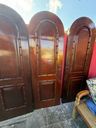 Portas de madeira maciça, estilo clássico colonial com arco e frisos trabalhados. 